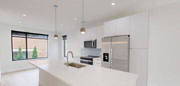 Modern minimalist kitchen with white cabinetry and stainless steel appliances at The 616.