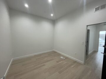 Empty room with wood flooring and open door.