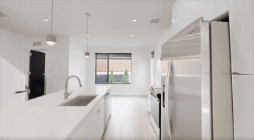 Modern minimalist kitchen with stainless steel appliances and white cabinetry at The 616.