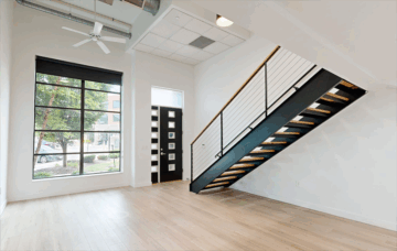 Modern loft-style interior with staircase and large window.