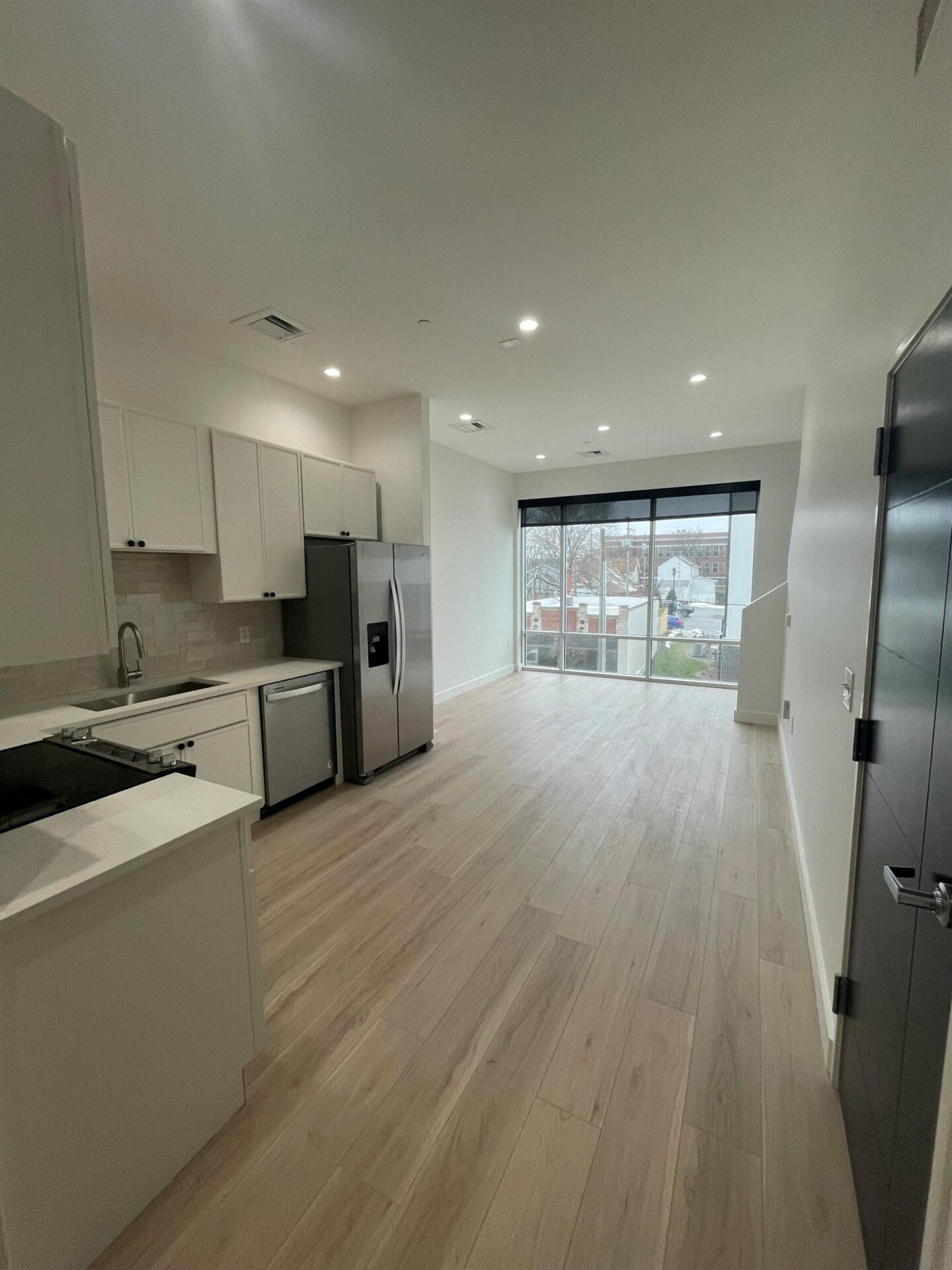 Modern kitchen with wood floors and large windows.