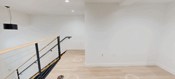 Modern minimalist hallway with railing and pendant light.