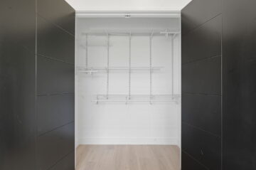 Empty walk-in closet with black walls and white wire shelves, modern interior design, minimalist storage space, The 616.