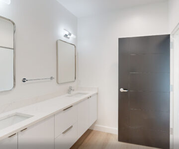 Modern white bathroom with double vanity and dark door