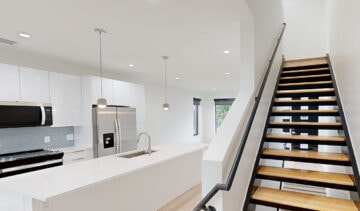 Modern minimalist kitchen with sleek white cabinets and stainless steel appliances at The 616 building.