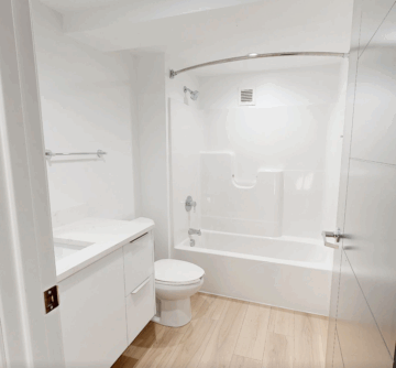 Modern white bathroom with tub and wooden floor.