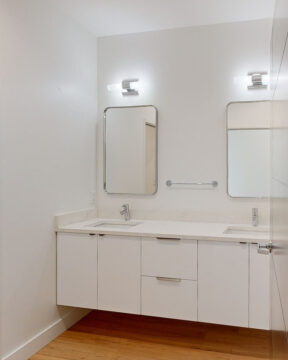 Modern bathroom with double sink and mirrors.