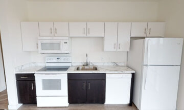 Clean apartment kitchen with white appliances and marble countertops