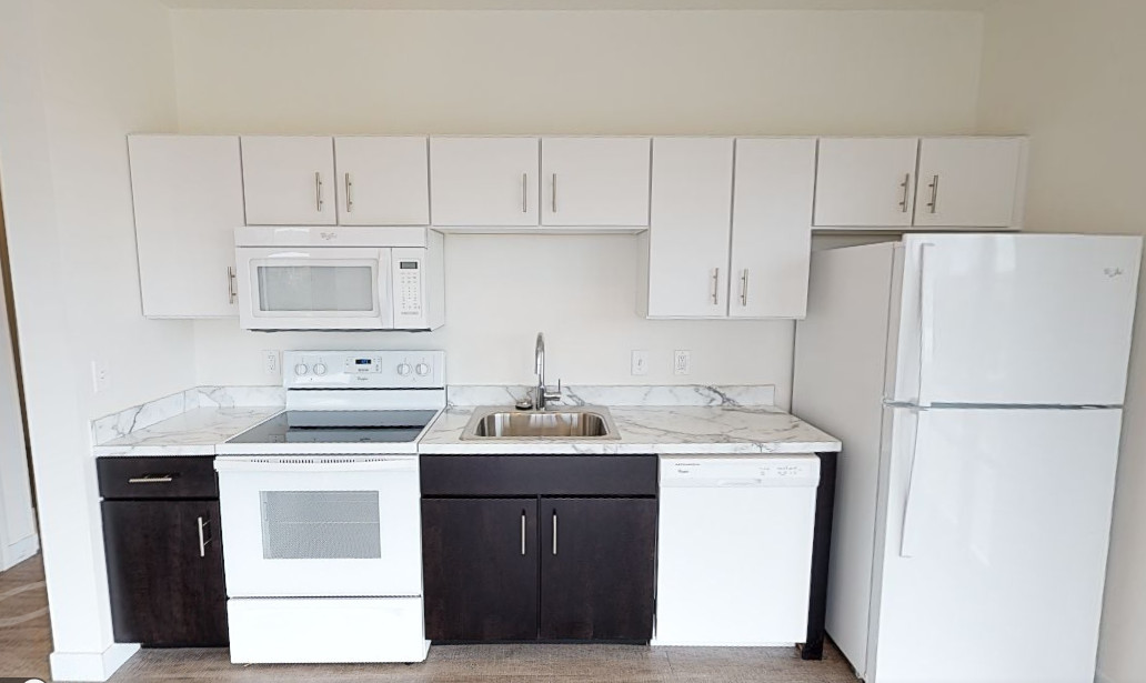 Clean apartment kitchen with white appliances and marble countertops