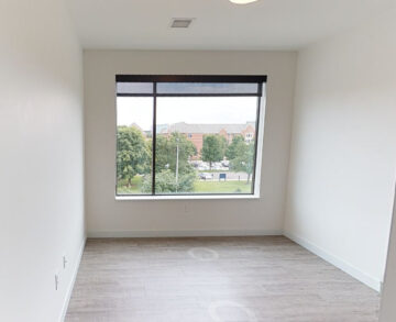 Empty modern room with large window overlooking urban neighborhood