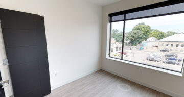 Empty modern apartment room with large window and black door