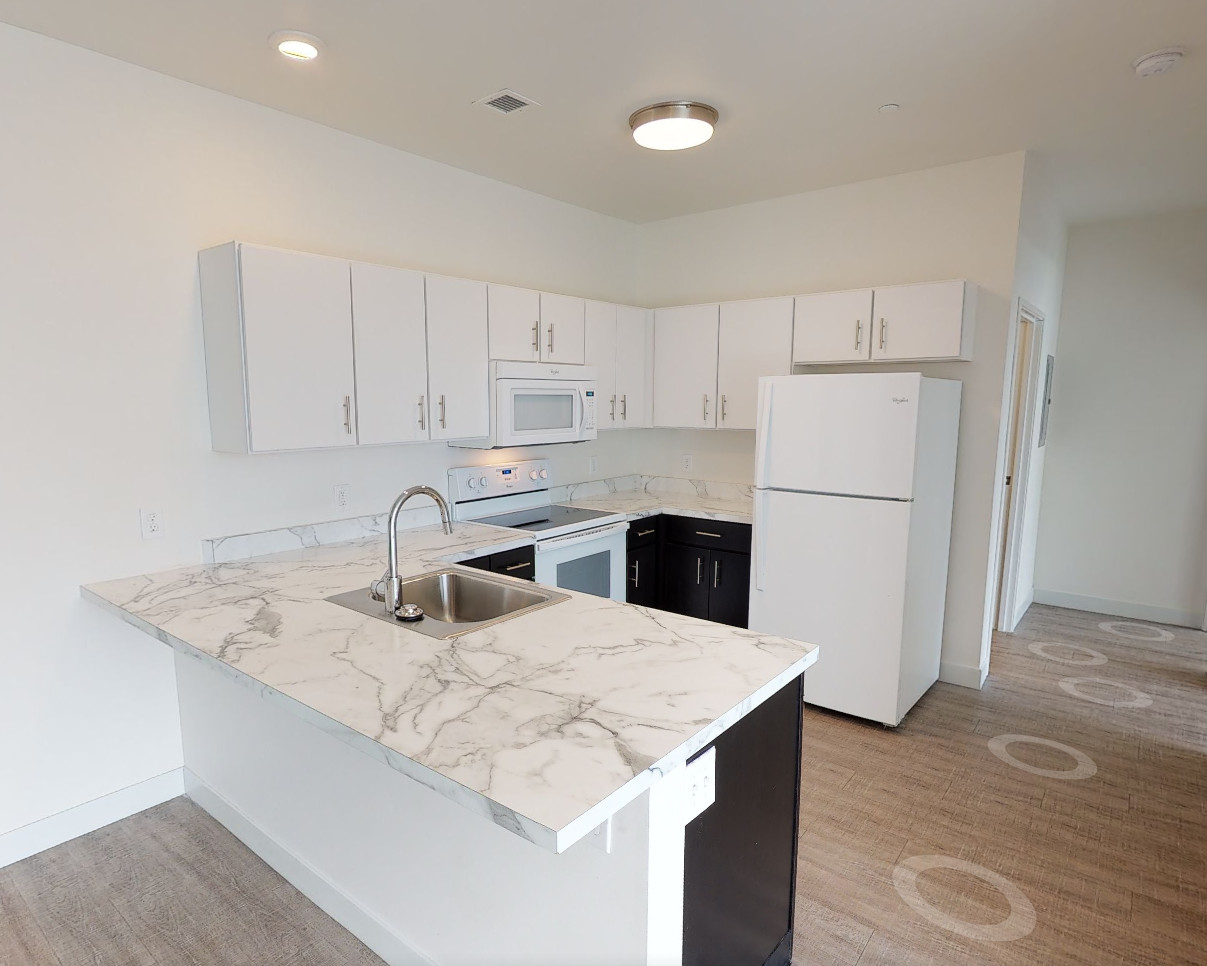 Modern kitchen with marble countertops and white appliances