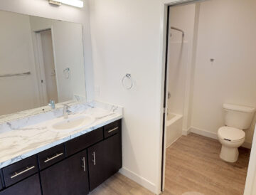Modern bathroom with double vanity, marble countertop, and shower
