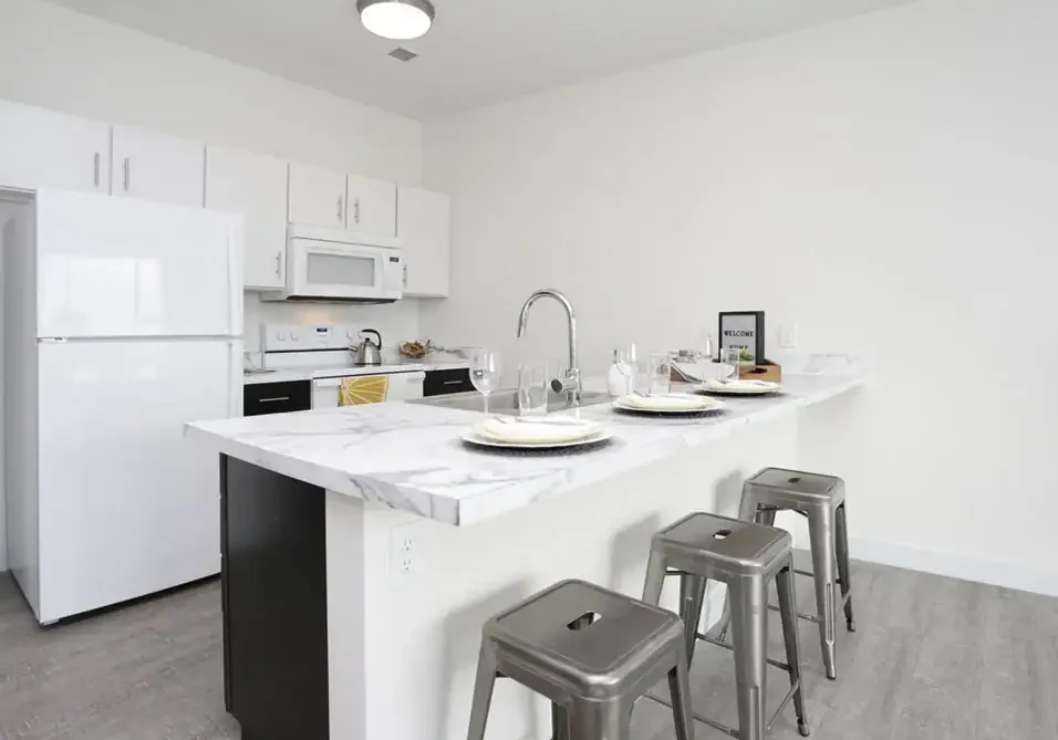 Modern white kitchen with marble island and stainless steel stools at The 616.