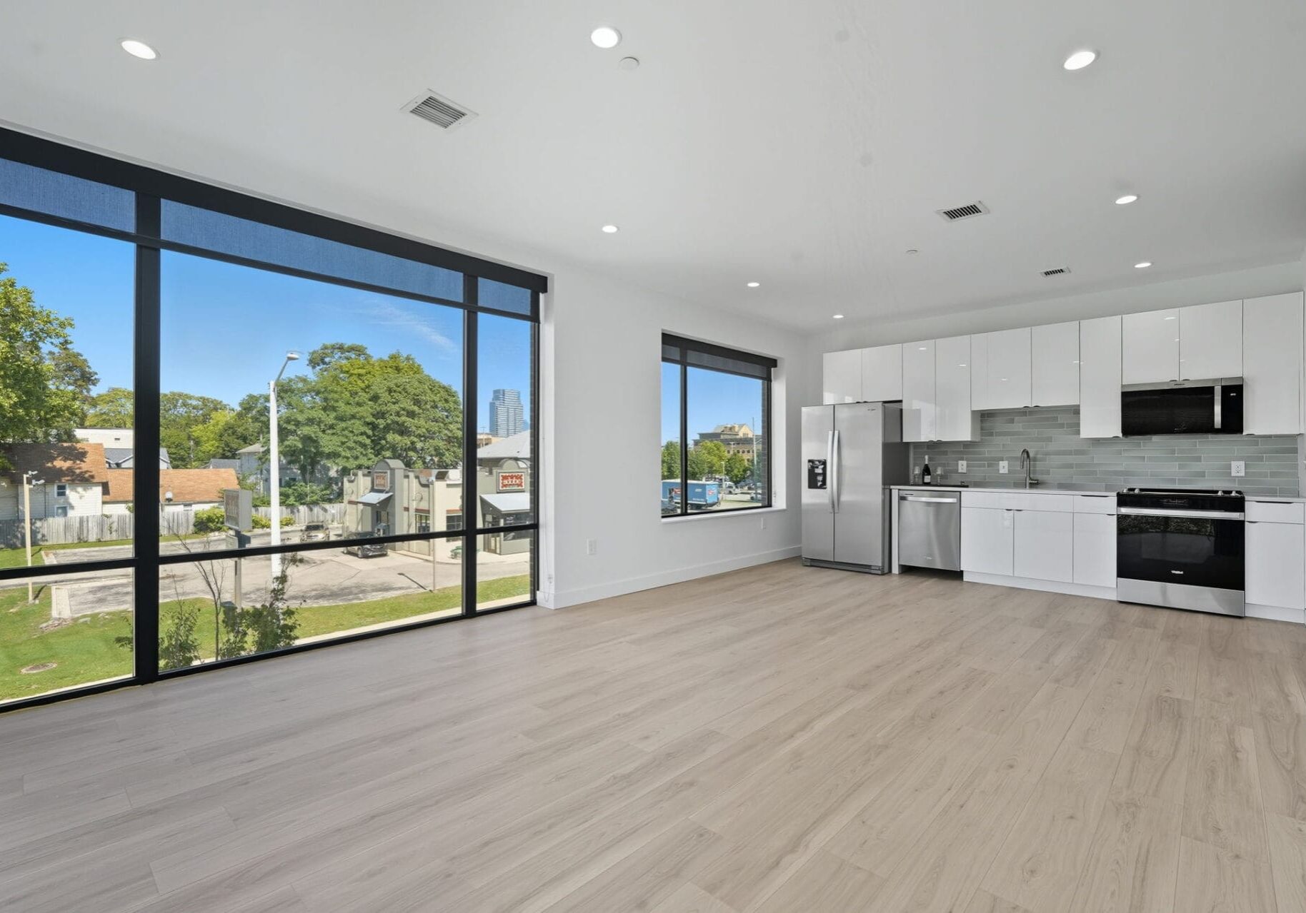 Modern minimalist kitchen with large windows and light wood flooring, ideal for urban apartment living.