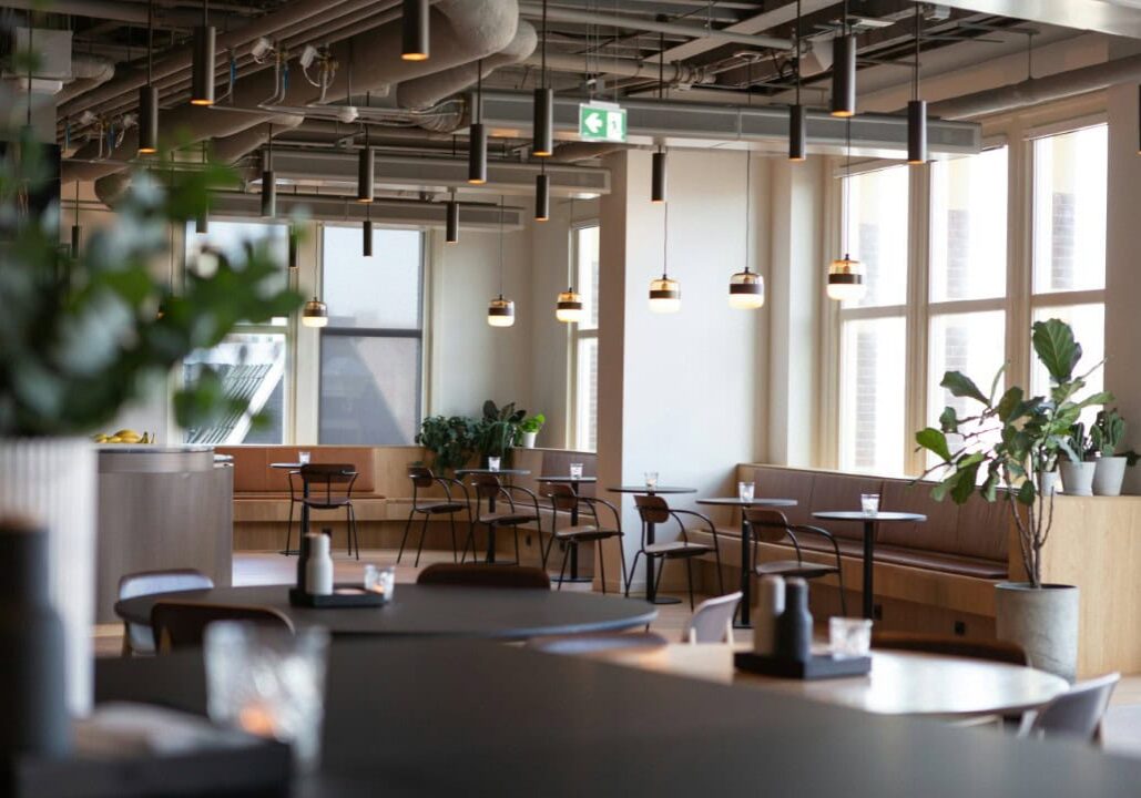 Modern cafe interior with tables and plants.