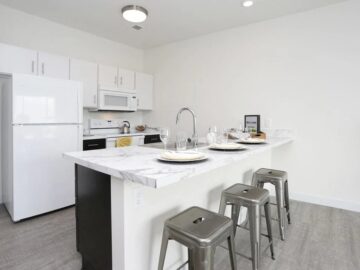 Modern white kitchen with marble island and metal barstools