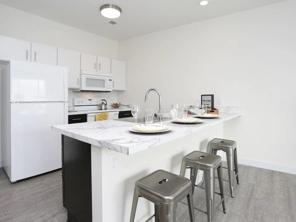 Modern white kitchen with marble island and metal barstools